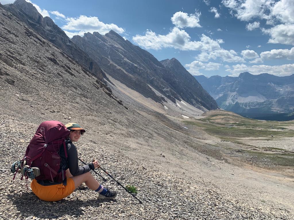 Backpacker carrying overnight gear in mountain terrain where shelter weight and packed size matter